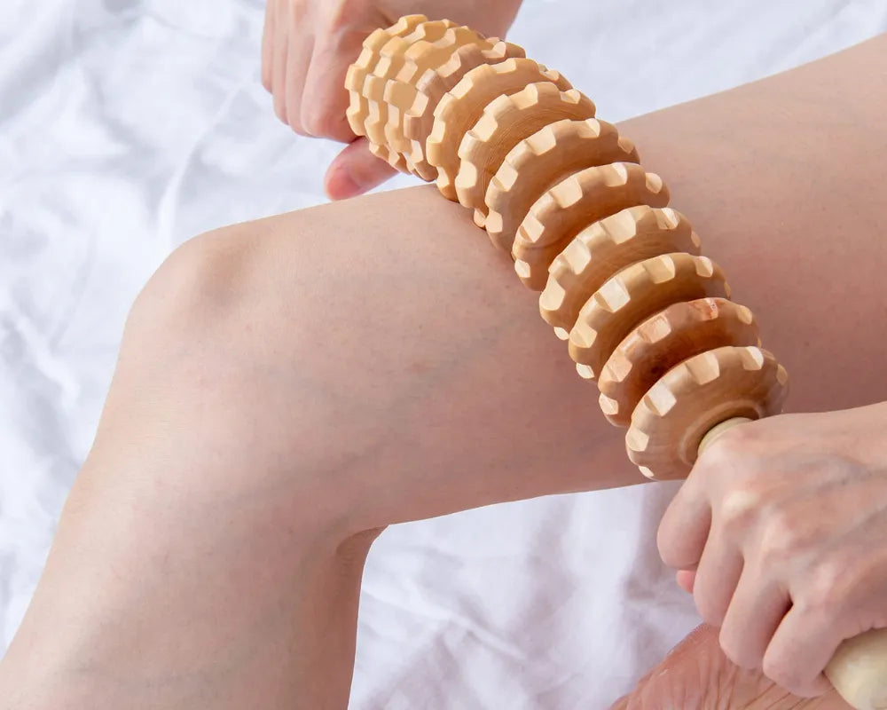 Rouleau de massage en bois sur la jambe